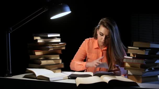 La ragazza legge e scrive informazioni in un quaderno. Fondo nero — Video Stock