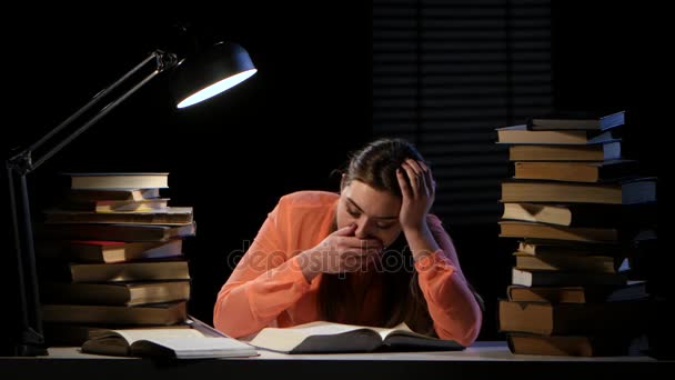 Una chica hojeando un libro bosteza y se queda dormida. Fondo negro — Vídeo de stock