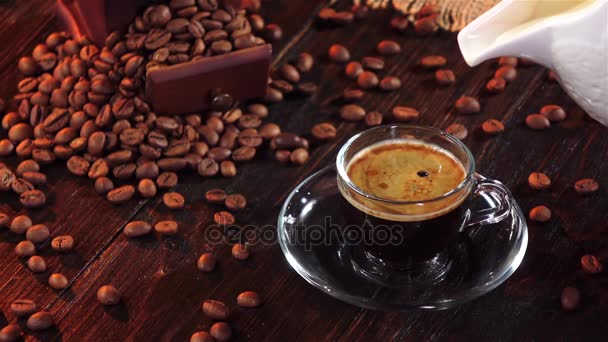 Cream is added to black coffee into transparent glass cup — Stock Video