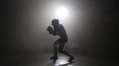 Şampiyon kick boks şampiyonu duman sayaç yumruklar evades. Siluet. Siyah arka plan. Yan görünüm