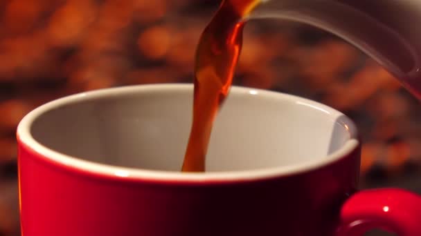 Café noir versé de la cafetière dans une petite tasse rouge. Gros plan 