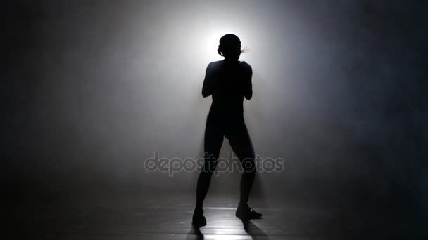 Kampioen bokser in de rook stuurt kicks. Silhouet. Verlichting achteraan. Zwarte achtergrond — Stockvideo