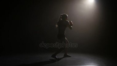 Şampiyonu boksör yumruklarını gönderir. Siluet. Işıklar arka. Siyah arka plan. Yan görünüm