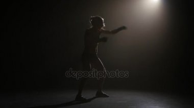 Şampiyonu boksör yumruklarını gönderir. Siluet. Işıklar arka. Siyah arka plan. Yan görünüm