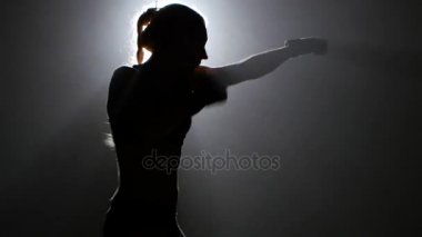 Şampiyonu boksör yumruklarını gönderir. Siluet. Siyah arka plan. Yan görünüm