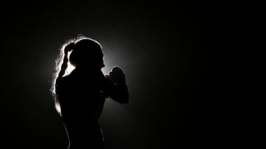 Kız rakip isabet bir boksör gönderir. Siluet. Siyah arka plan. Yan görünümü. Yakın çekim