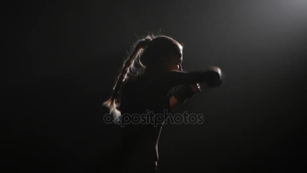 Mädchen schickt einen Boxer, der Gegner schlägt. Silhouette. schwarzer Hintergrund. Seitenansicht. Nahaufnahme — Stockvideo
