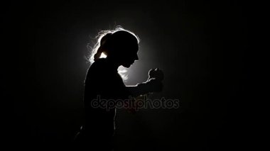 Kadın boksör bir rekabet için hazırlanıyor. Ağır çekim. Siyah arka plan. Yan görünümü. Siluet