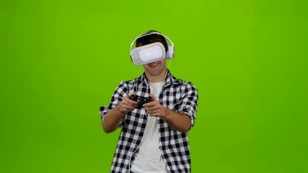 Чоловік грає на ігровому автоматі з навушниками та окулярами vr. студії — стокове відео