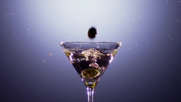 Slow motion. Green fresh olives fall into glass with cocktail — Stock Video