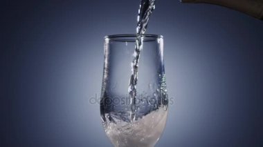 Şampanya şarap şeffaf cam bardak içine dökülür. Mavi arka plan