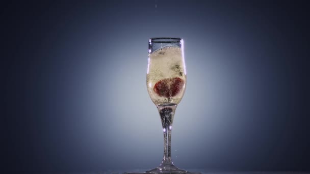 Zeitlupe, im Glas mit Champagner, der auf frische Erdbeeren fällt — Stockvideo