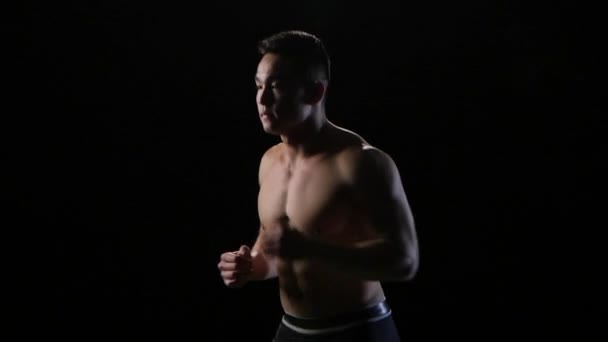 Sportman uitvoeren op een zwarte achtergrond in slow motion. Midden afstand — Stockvideo