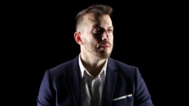 Tıraşsız adam endişeyle bekliyor ve saate benziyor. Siyah arka plan