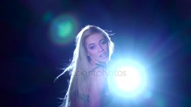 Sarışın kadın pj dansları siyah arka plan, arkasında parlak spot