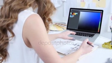 Sanatçı bilgisayar bakar ve tonları giyim yeni bir koleksiyon için seçer