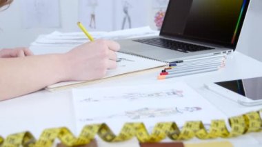 Moda Tasarımcısı yeni bir koleksiyon için skeçler çizer ve bilgisayar bakar