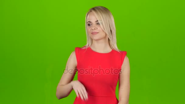 Chica en rojo sobre fondo de pantalla verde muestra su mano — Vídeos de Stock