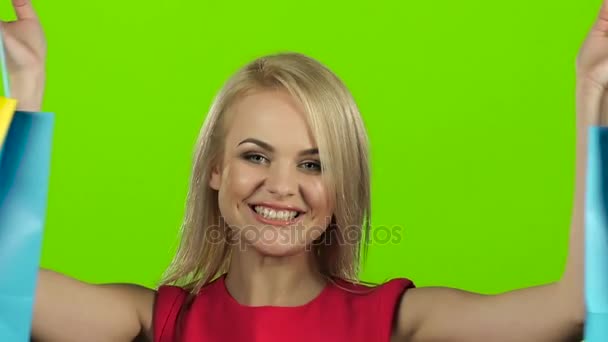 Chica rubia con paquetes de colores muecas y sonrisas. Movimiento lento — Vídeo de stock