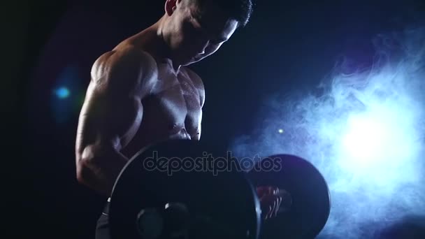 Azjatycka muskularny mężczyzna biceps trening ze sztangą. Na tle czarnego dymu. Zwolnionym tempie — Wideo stockowe