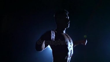 Asya kaslı adam gösterir kasları gösterir. Siyah arka plan. Ağır çekim. Siluet