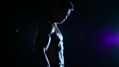 Atlet kasları bir dumbbell ile eğitiyor. Siyah arka plan. Ağır çekim. Siluet