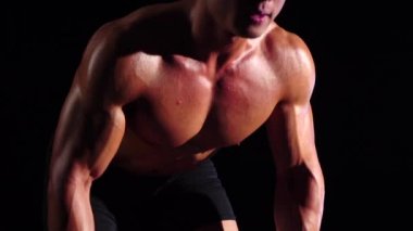 Vücut geliştirmeci bir halter ile çalışmaları yapar. Siyah arka plan. Ağır çekim. Yakın çekim