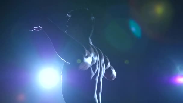 Aziatische atleet toont zijn gabbled spieren. Zwarte achtergrond. Slow-motion. Silhouet — Stockvideo