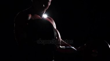 Vücut geliştirmeci eğitim pazı bir halter ile. Siyah duman arka plan. Ağır çekim