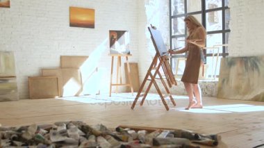 Kadın sanatçı şövale üzerinde tuval üzerine boya ve palet sanat atölyesinde tutar
