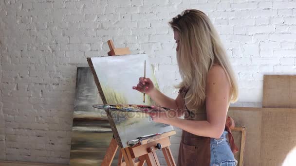 Donna artista dipinge quadro nel suo negozio di lavoro, vista laterale — Video Stock