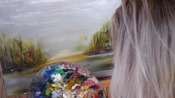 Artiste blonde peint des peintures à l'huile sur toile. Détails, vue de face — Video