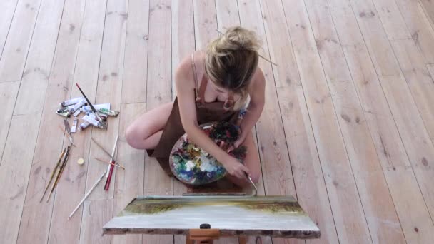 Artista feminina pinta obra-prima sentada no chão. Vista superior — Vídeo de Stock