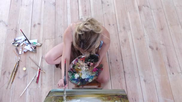 Γυναίκα καλλιτέχνης ζωγραφίζει εικόνα κάθεται στο πάτωμα. Το Top view — Αρχείο Βίντεο