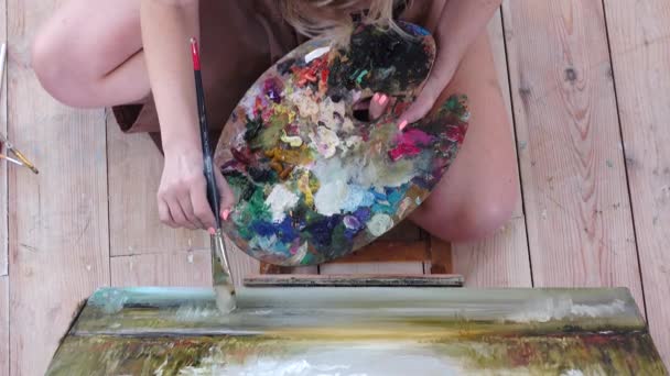 Девушка-художник рисует картину, сидя на полу. Вид сверху — стоковое видео