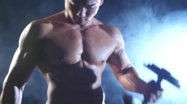 Kaslı adam spor salonunda eğitim pazı siyah duman arka plan salıncaklar