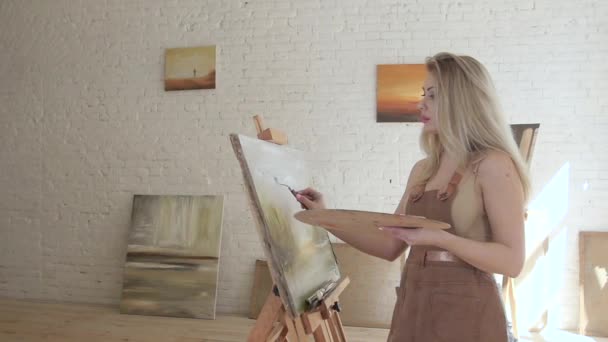 Meisje kunstenaar verven op canvas op ezel in slow motion — Stockvideo