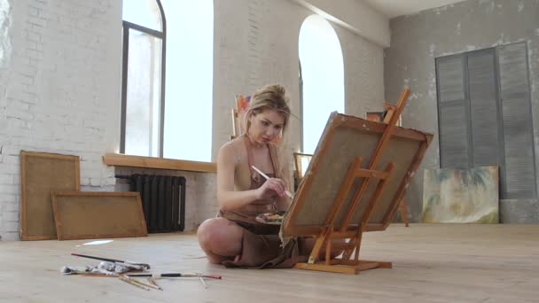 Καλλιτέχνης ζωγραφίζει αριστούργημα που κάθονται στο πάτωμα, αργή κίνηση. Πλάγια όψη — Αρχείο Βίντεο