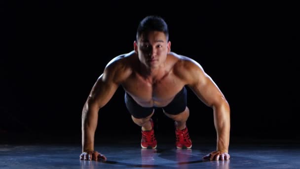 Aziatische atleet push ups, samendrukking van de vloer, hij is sterk en hardy. Zwarte achtergrond — Stockvideo