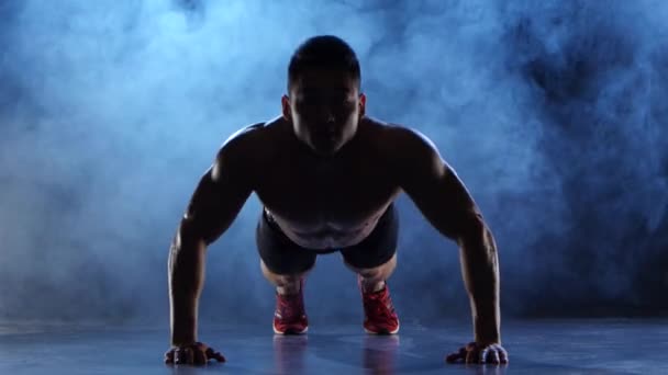 Aziatische bodybuilder man push-ups. Zwarte rook achtergrond. Silhouet — Stockvideo