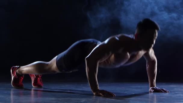 Sportler drückt vom Boden weg, er ist zielstrebig und hartnäckig. schwarzer Rauchhintergrund. Silhouette — Stockvideo