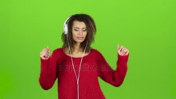 Kobieta tańczy seksualnie z słuchawkami na zielonym ekranie. Zwolnionym tempie — Wideo stockowe