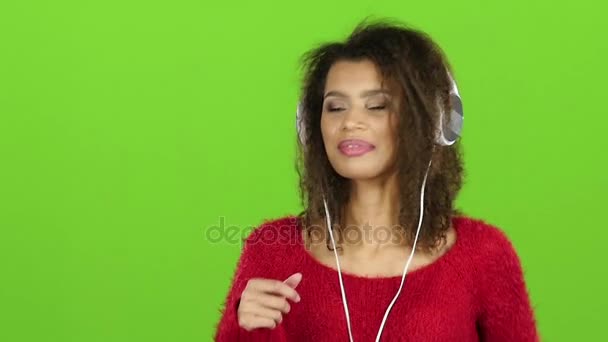 ヘッドフォン、緑色の画面と踊るアフロ アメリカン ガール。スローモーション — ストック動画