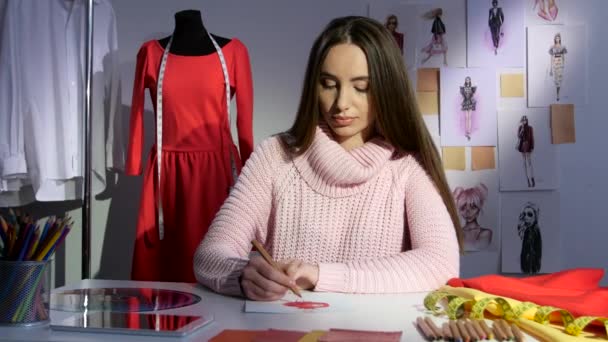 Modedesigner ritar en skiss av en röd klänning, workshop — Stockvideo