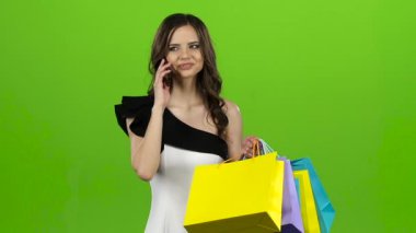 Esmer telefonda konuşuyor, o onun elinde paketleri bir yeri vardır. Yeşil ekran. Ağır çekim