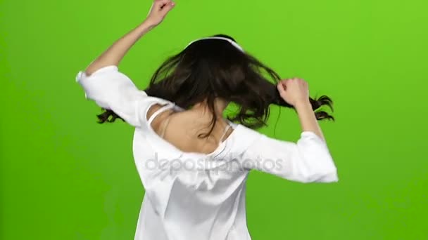 Brunette with headphones in her ears is having fun. Green screen. Slow motion — Stock Video
