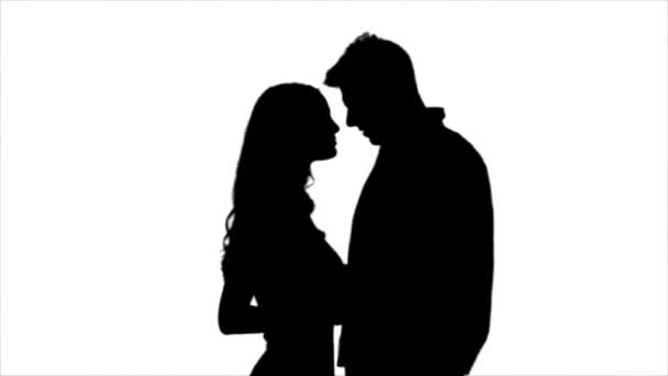 Loving couple look at each other and begin to kiss. Silhouette. White background. Slow motion — Stock Video