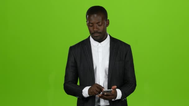 African tient un téléphone et feuillette les informations. Écran vert — Video