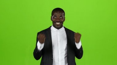 Afrika kökenli Amerikalı sıkı siyah elbiseli zaferi ile mutlu. Yeşil ekran. Ağır çekim