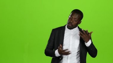 Afrika kökenli Amerikalı adam dansları ile bir iş takım elbise, onun komik hareketler var. Yeşil ekran. Ağır çekim